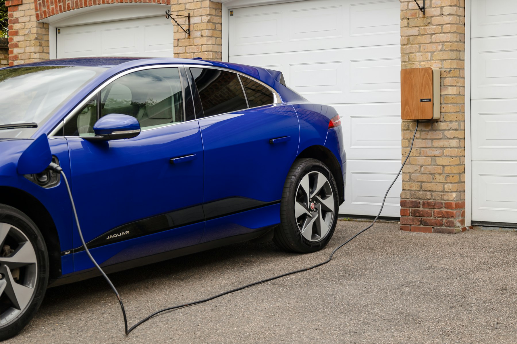 Sähköauto latautuu autotallin seinään asennetusta latausasemasta